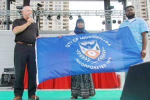 From Left to Right: Mississauga Ward 6 Councillor Ron Starr presents the flag of the city to MuslimFest's Rina Rahman, artistic development & management and legal advisor, MuslimFest and Saffraz Khan, event director, MuslimFest 2013.