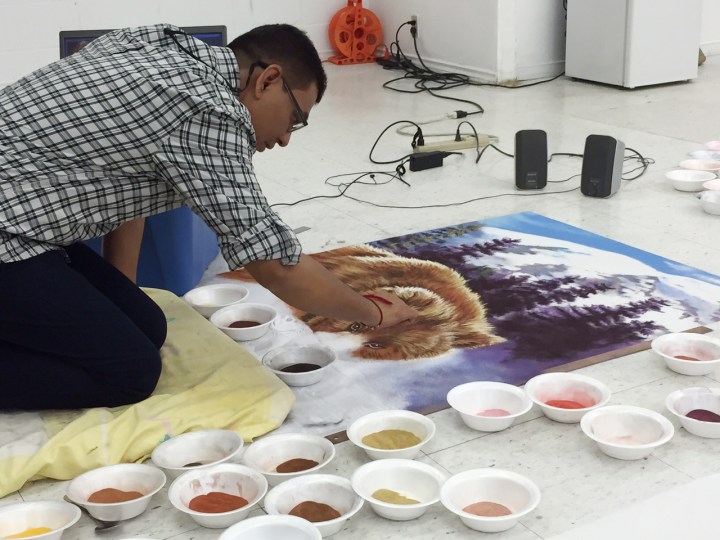 Canadian artist Praksh Shirke fills in the snout of a grizzly bear with coloured sand. Prakash has taken the ancient Indian art of Rangoli and transformed it.
