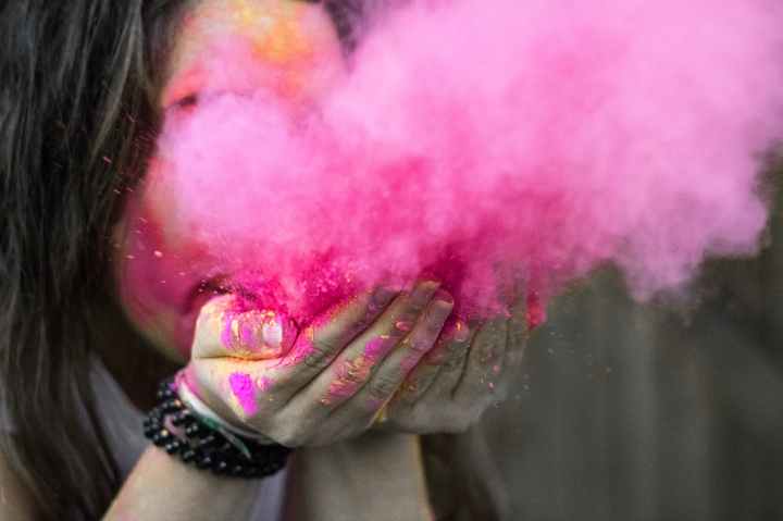 Woman blows a plume of pink colour